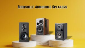 Three bookshelf speakers on a marble podium against a yellow background.